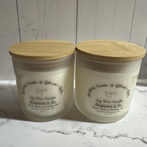 Two scented candles with wooden lids on a marble surface.