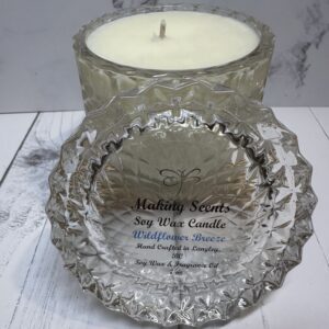 A scented soy wax candle with a textured glass container and lid.