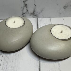 Two smooth, round gray candle holders with white tealight candles.