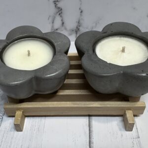 Two flower-shaped candles on a wooden stand.