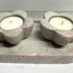Two heart-shaped stone candle holders with white candles on a matching stone base.