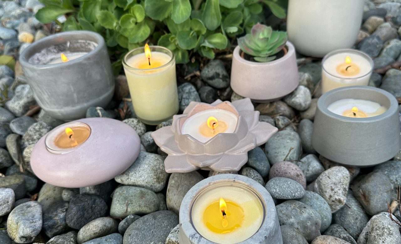 Decorative candles and succulents arranged on smooth stones.