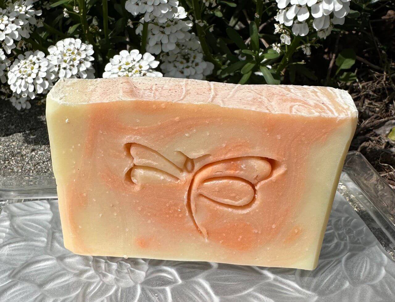 Handmade soap bar with a butterfly imprint and floral background.