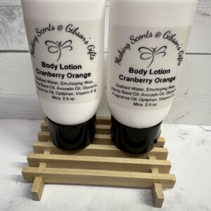 Two tubes of cranberry orange body lotion on a wooden rack.