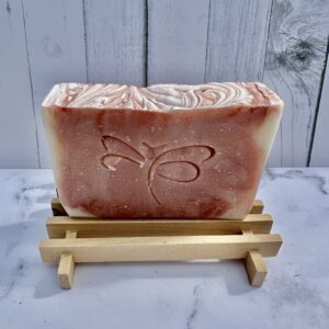Handcrafted soap with a butterfly design on a wooden stand.
