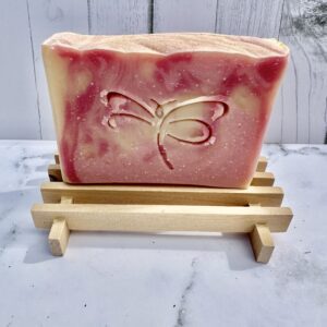 Artisan soap with a butterfly design on a wooden soap dish.