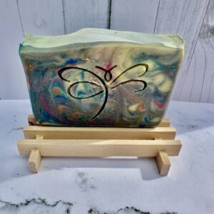 Colorful resin soap with butterfly design on wooden stand.