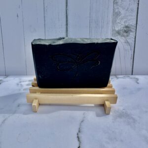 Black planter on a small wooden stand against a white wooden background.