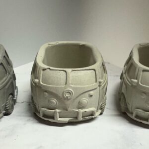 Three gray cement planters shaped like vintage vans.