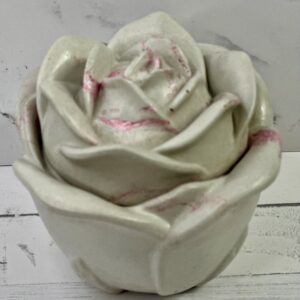 A delicate white rose sculpture with subtle pink accents.