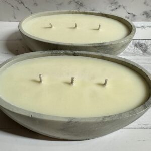 Two oval concrete candles with multiple wicks on a marble surface.